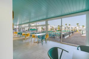 stołówka ze stołami i krzesłami oraz widokiem na plażę w obiekcie Bitacora Lanzarote Club w Puerto del Carmen