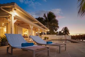 een patio met 2 ligstoelen en een zwembad bij Serenity by the Sea- 3BRVilla w Stunning Sunsets in Tamarin
