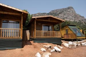 a log cabin with a mountain in the background at Goat Bungalow and Camping in Faralya