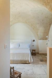 a bedroom with a white bed and a stone floor at Masseria Gorgognolo in Ostuni