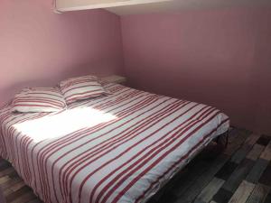 ein Schlafzimmer mit einem Bett mit einer gestreiften Decke in der Unterkunft Villa avec piscine, parking, clim in Palavas-les-Flots
