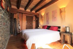 1 dormitorio con 1 cama grande y pared de piedra en Hotel Rural La Encantada en Riaza, en Becerril