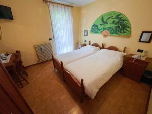 1 dormitorio con cama, escritorio y ventana en Albergo Nuoitas, en Forni di Sopra