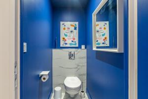 a blue bathroom with a toilet and a blue wall at Le Loft du Parvis : spacieux, central & élégant. in Dijon +12 photos