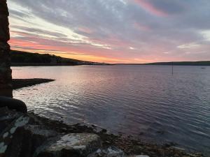 a view of a large body of water at sunset at Waterfront Apartment, St Margarets Hope, Orkney in St Margaret's Hope