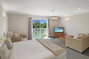 Kerikeri Park Lodge في كيريكيري: غرفة نوم بسرير ابيض كبير وتلفزيون