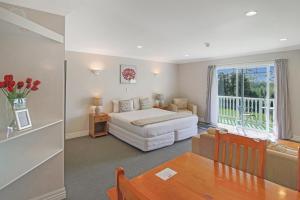a bedroom with a bed and a table and a window at Kerikeri Park Lodge in Kerikeri