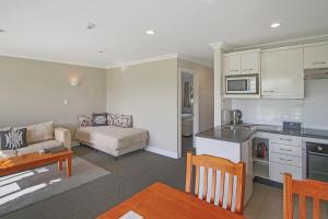 a kitchen and a living room with a couch at Kerikeri Park Lodge in Kerikeri