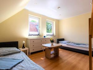 1 dormitorio con 2 camas, mesa y 2 ventanas en Großzügige Ferienwohnung im Haus ''Anno 2000'', en Bergen auf Rügen