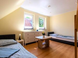 a bedroom with two beds and a table and two windows at Großzügige Ferienwohnung im Haus ''Anno 2000'' in Bergen auf Rügen