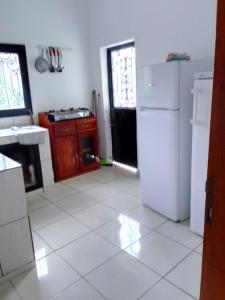 a kitchen with white tile floors and a white refrigerator at Pauline in Yaoundé