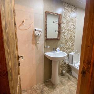 ein Badezimmer mit einem Waschbecken, einem Spiegel und einem WC in der Unterkunft Arte Jermuk Cottages in Dschermuk