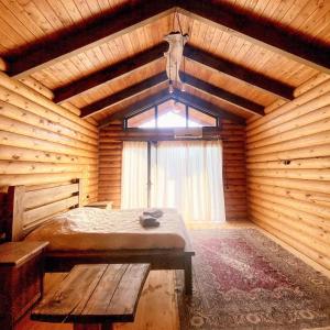 a bedroom in a wooden cabin with a bed and a window at Arte Jermuk Cottages in Jermuk