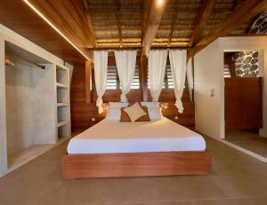 a bedroom with a large bed with white sheets at Marie-Louise - cocon pieds dans l'eau - Boucan Canot in Saint-Gilles les Bains