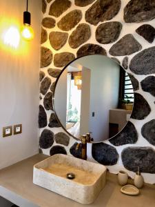 uma casa de banho com uma parede de pedra e um espelho grande em Marie-Louise - cocon pieds dans l'eau - Boucan Canot em Saint-Gilles-les-Bains