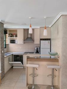 a kitchen with white cabinets and bar stools at House Laguna Roja in Torrevieja