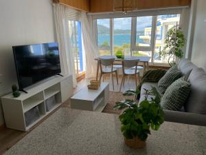 a living room with a couch and a tv and a table at Apartamento con vistas al mar Urb Puerto Azul B3 in Cedeira