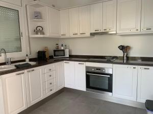 cocina blanca con armarios blancos y microondas en Big house with swimming pool, en Segur de Calafell