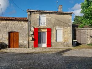 een rode deur op een stenen huis met een garage bij Gite chez Lea in Saint-Seurin-de-Cadourne