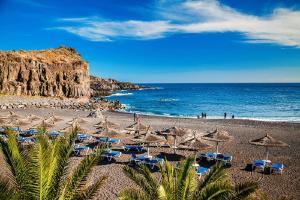 a beach with chairs and umbrellas and the ocean at ocean experience / EXPERIENCE HOLIDAYS TENERIFE in Callao Salvaje