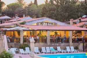 a resort with a pool and chairs and a restaurant at ISA-Residence with swimming pool in Guardistallo surrounded by greenery in Casale Marittimo