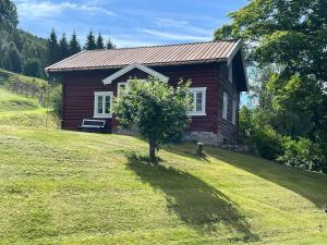 ein kleines Haus auf einem Hügel mit einem Baum davor in der Unterkunft « SoFly Cottage », le charme pur in Noresund