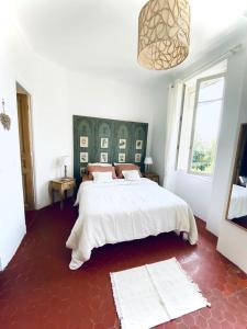 ein Schlafzimmer mit einem großen weißen Bett und einem Fenster in der Unterkunft Le Jardin D'Elma in Vence