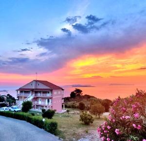 un edificio rosa con una puesta de sol en el fondo en Nikos Apartments Corfu, en Agios Stefanos