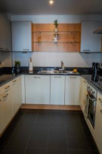 a kitchen with white cabinets and a sink at Stunning Modern Apartment in the Gasworks in Dublin
