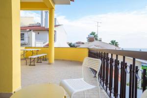 a balcony with chairs and tables and a yellow wall at Kubata Hill in Parede