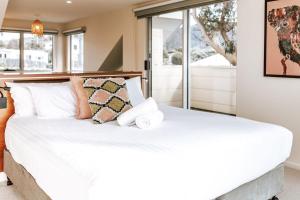 sypialnia z dużym łóżkiem z białą pościelą i poduszkami w obiekcie Cod Rock Point w mieście Bicheno