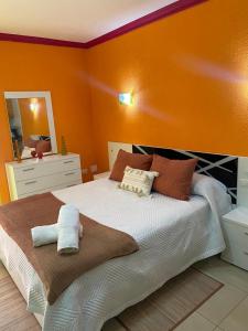 - une chambre avec un grand lit aux murs orange dans l'établissement ARCOIRIS AL MAR, à San Marcos