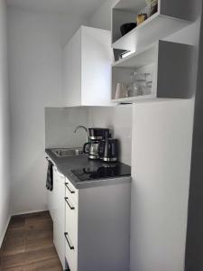 una pequeña cocina con armarios blancos y fregadero en White Boutique Homes - Euphoria, en Metókhion Apisianá