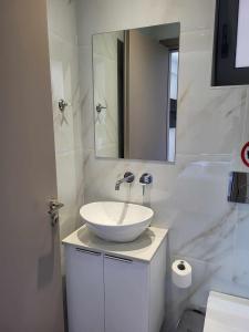 Baño blanco con lavabo y espejo en White Boutique Homes - Euphoria en Metókhion Apisianá