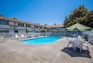 a swimming pool with chairs and a table and umbrella at Quality Inn & Suites Medford Airport in Medford
