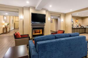 a living room with a blue couch and a fireplace at Comfort Inn & Suites IAH Bush Airport - East in Humble