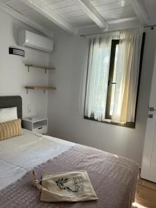 a white bedroom with a bed and a window at Agrielia Studios Katigiorgis, Agios Georgios in Agios Georgios