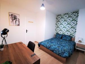 Schlafzimmer mit einem Bett und einem Holztisch in der Unterkunft Le T3 Confort - Au Cœur de Montceau in Montceau-les-Mines
