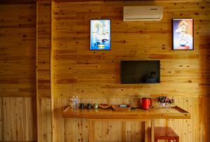 a room with a wooden wall with a table and a television at Mường Hoa River View Homestay in Sapa