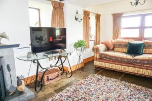sala de estar con sofá y TV en Gars Cottage - 3 Bedroom Holiday Home, en Kirkby Stephen