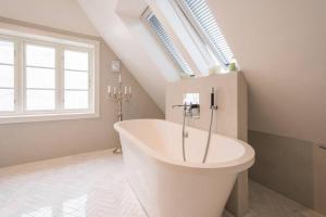 a white bathroom with a tub in a attic at Beautiful townhouse super Central in Bergen - 4 bedrooms 8 guests in Bergen