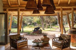 ein Wohnzimmer mit 2 Stühlen, einem Tisch und einem Kamin in der Unterkunft Simbavati Camp George in Klaserie Private Nature Reserve