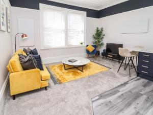 a living room with a yellow chair and a table at Apartment 4 in Grimsby