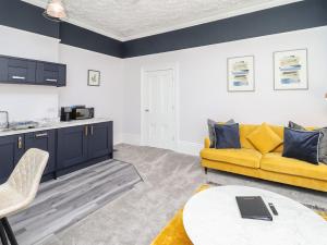 a living room with a yellow couch and a table at Apartment 4 in Grimsby