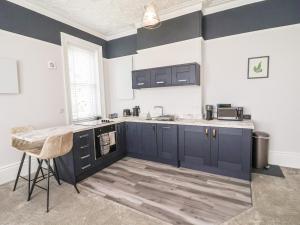 uma cozinha com armários azuis e uma bancada em Apartment 4 em Grimsby