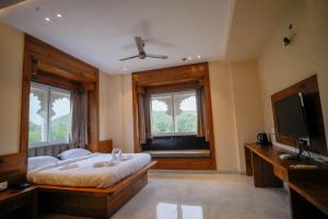 a bedroom with a bed and a tv and windows at The Ekling Garh Hotel & Resort in Udaipur