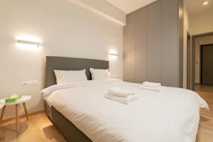 sypialnia z dużym białym łóżkiem z ręcznikami w obiekcie Luminus and roomy in Pagrati w Atenach