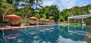 una piscina con sedie e ombrelloni in un resort di Gran Melia Jakarta a Giacarta