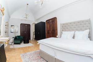 een slaapkamer met een groot wit bed en een groene stoel bij Villa Zara Boutique Hotel Resort in Smolník