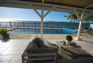 a patio with a couch and a swimming pool at Serenity by the Sea- 3BRVilla w Stunning Sunsets in Tamarin